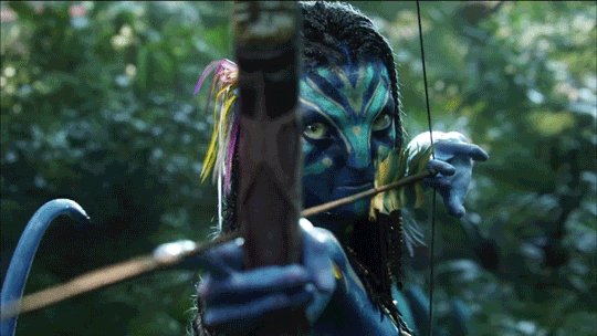 a moving gif image of Avatar character Neytiri shoooting an arrow past the camera